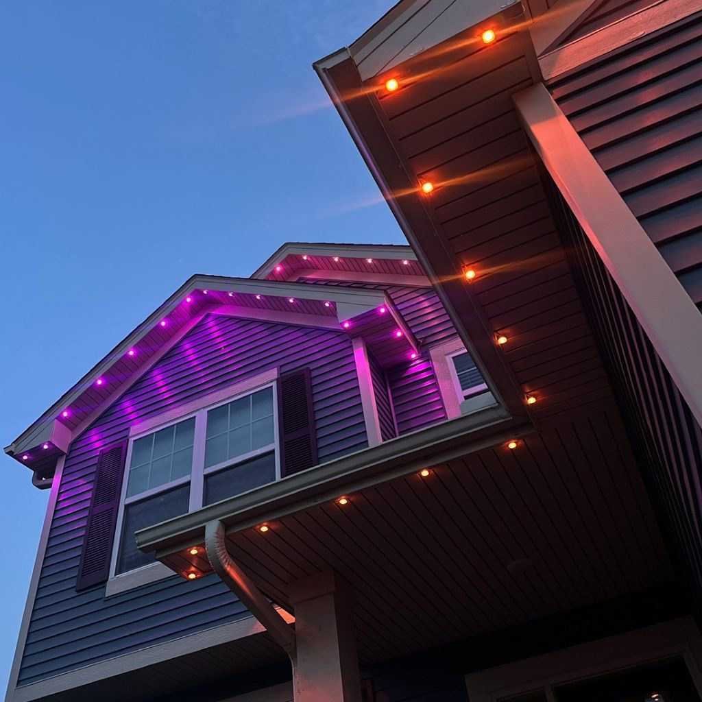 Purple and orange accent lighting along the gables and soffits of a home for Halloween