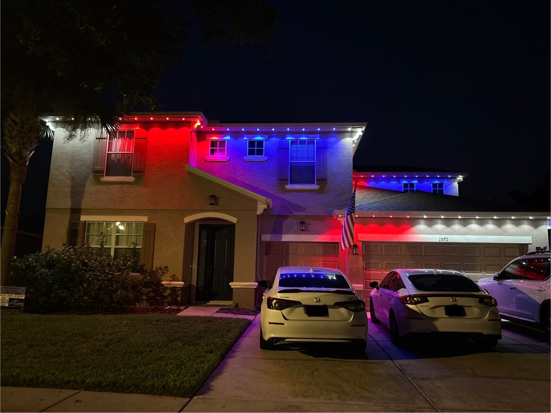 Red, orange, and blue LED lighting on three roof gables of a home at night