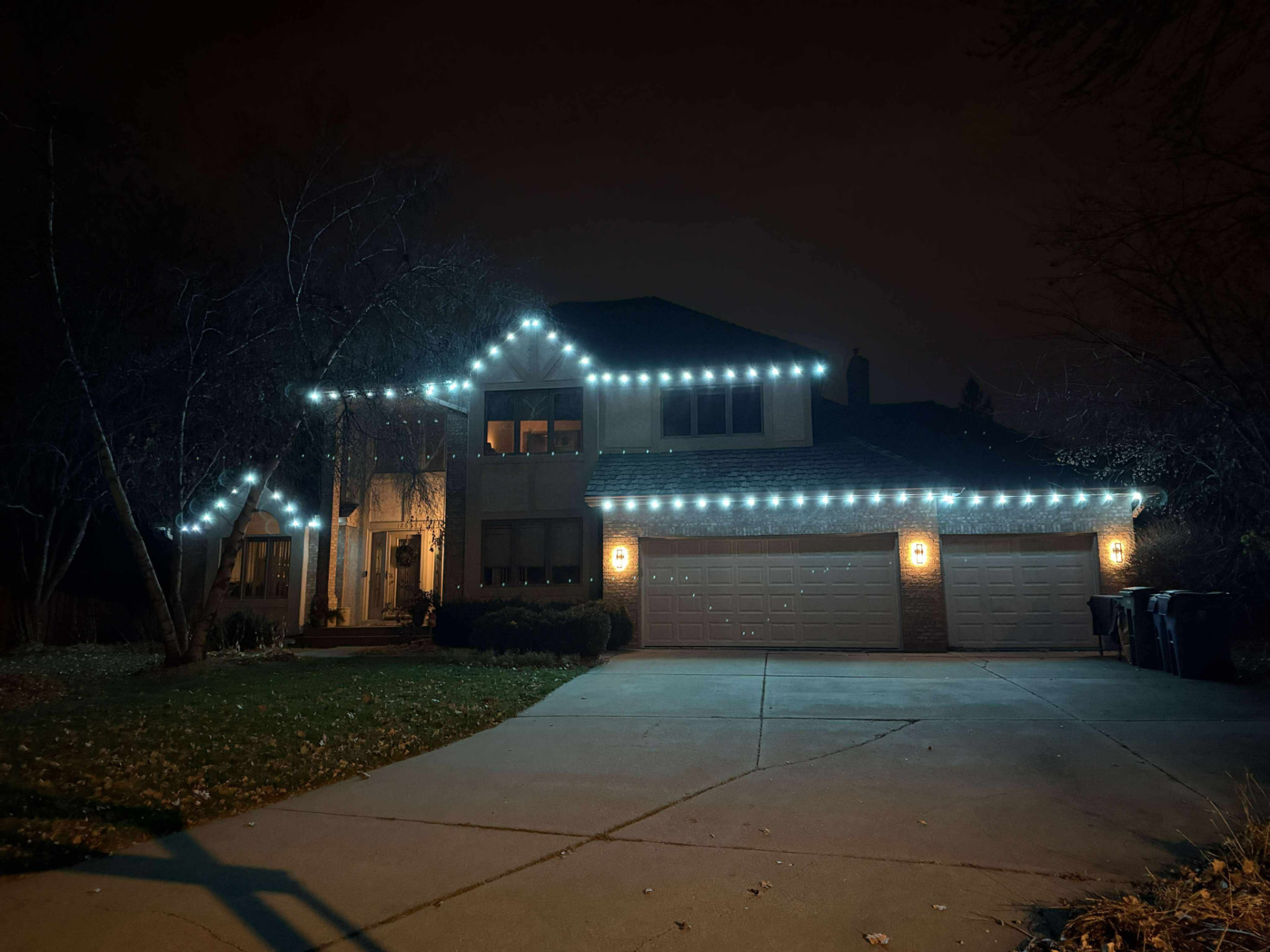 Red, white, and blue LED lighting across a tan stucco home with an American flag by the garage